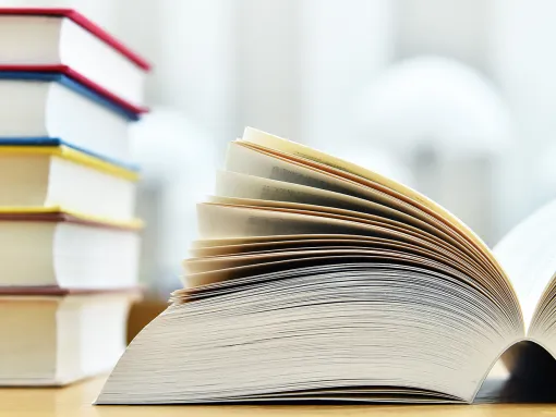 Library books on a table with a book open to the center